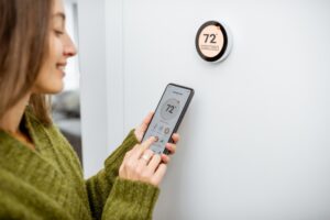 woman-changes-temperature-on-smart-thermostat-with-smart-phone